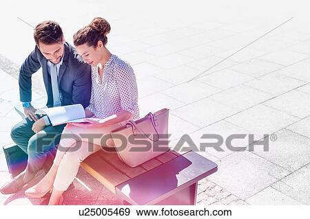 High angle view of businesswoman discussing plans over document with businessman while sitting on bench View Large Photo Image Stock Photo - High angle view of businesswoman discussing plans over document with businessman while sitting on bench. Fotosearch