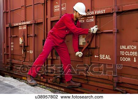 Stock Image - Hispanic worker opening industrial railway carriage. Fotosearch