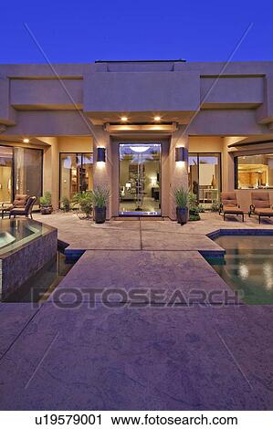 Stock Image - House exterior with pool at dusk. Fotosearch
