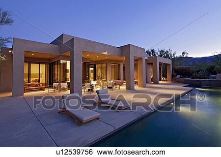 Stock Photograph - House exterior with pool at dusk. Fotosearch