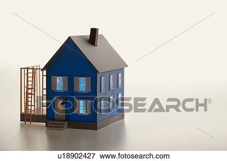 Stock Photo - Illuminated model house with ladder and extension. Fotosearch