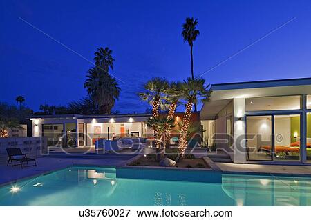 Stock Photo - Illuminated patio at poolside in luxurious villa at night. Fotosearch