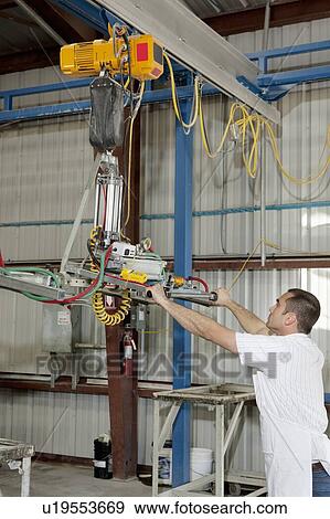 Stock Photo - Industrial worker adjusting machinery in factory. Fotosearch