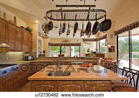 Stock Image - Kitchen counter with utensils hanging in luxury villa. Fotosearch