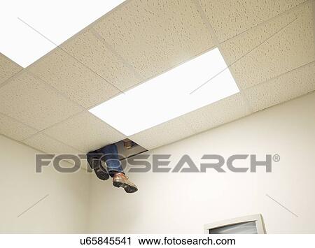 Stock Image - Legs peeping from hole in ceiling. Fotosearch