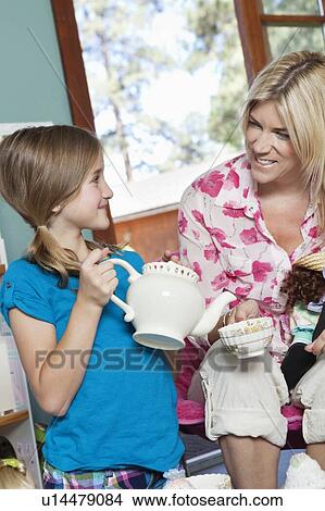 Little girl pretending to pour tea for her mother View Large Photo Image Picture - Little girl pretending to pour tea for her mother. Fotosearch