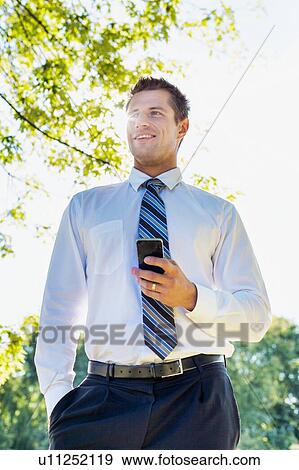 Stock Photo - Low angle view of handsome mature businessman using smartphone . Fotosearch