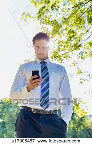 Low angle view of handsome mature businessman using smartphone View Large Photo Image Stock Photo - Low angle view of handsome mature businessman using smartphone . Fotosearch