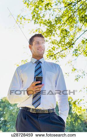 Stock Photo - Low angle view of handsome mature businessman using smartphone . Fotosearch