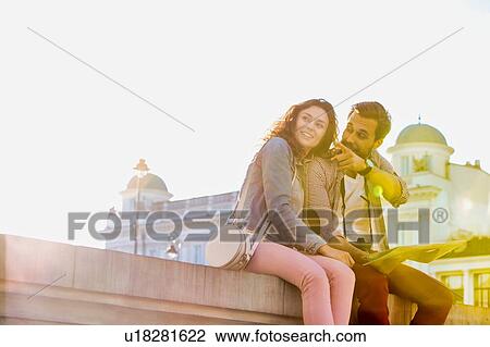 Low angle view of man holding map while sitting and talking to his girlfriend View Large Photo Image Stock Image - Low angle view of man holding map while sitting and talking to his girlfriend. Fotosearch