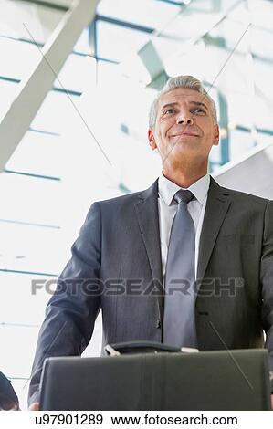 Low angle view of mature businessman queuing for check in at airport View Large Photo Image Stock Photo - Low angle view of mature businessman queuing for check in at airport. Fotosearch