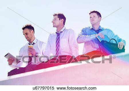 Low angle view of thoughtful mature businessmen sitting and relaxing on rooftop during break in office View Large Photo Image Stock Photography - Low angle view of thoughtful mature businessmen sitting and relaxing on rooftop during break in office. Fotosearch