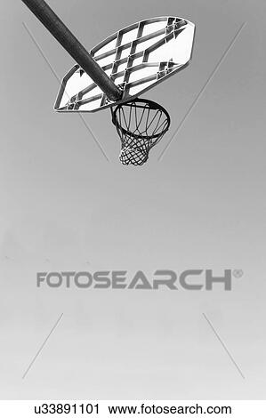 Stock Image - Low angled black and white photograph of a basket ball net and hoop and backboard. Fotosearch