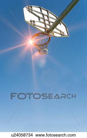 Picture - Low angled view of a basket ball net and hoop and backboard with strong sunshine lens flare. Fotosearch