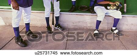Stock Photography - Low section of baseball player preparing for match in dugout. Fotosearch