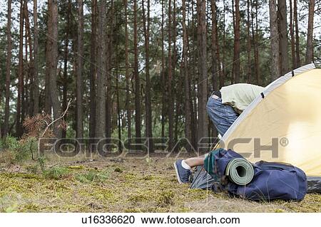 Stock Image - Low section of man entering tent in forest. Fotosearch