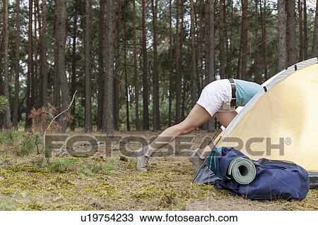 Stock Image - Low section of woman entering tent in forest. Fotosearch