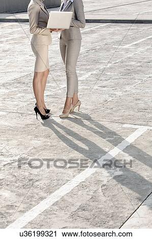 Low section of young businesswomen with laptop standing on street View Large Photo Image Stock Image - Low section of young businesswomen with laptop standing on street. Fotosearch