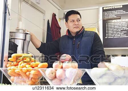 Picture - Male vendor at juice center. Fotosearch
