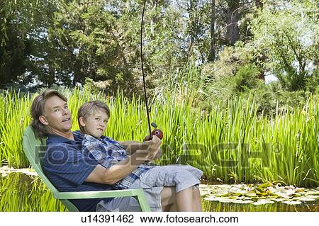 Stock Image - Man and son fishing together countryside. Fotosearch