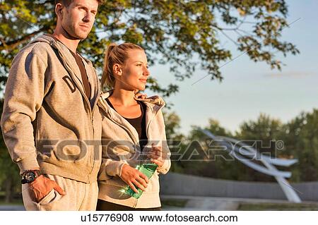 Stock Photo - Man embracing her girlfriend after work out in park with lens flare. Fotosearch