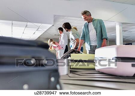 Man getting his suitcase on baggage claiming area in airport View Large Photo Image Stock Photo - Man getting his suitcase on baggage claiming area in airport. Fotosearch