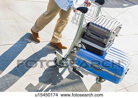 Picture - Man pushing cart with his luggage in airport. Fotosearch