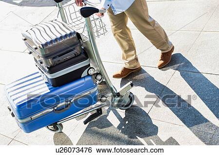 Man pushing cart with his luggage in airport View Large Photo Image Stock Photograph - Man pushing cart with his luggage in airport. Fotosearch