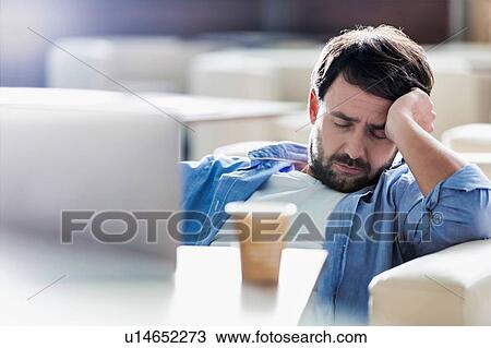 Stock Image - Man taking a nap while sitting and waiting for his flight in cafe at airport. Fotosearch