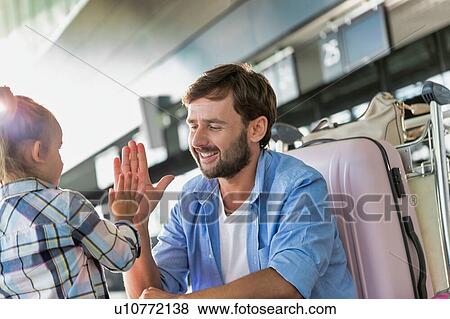 Man talking to his daughter and giving her a high five in airport View Large Photo Image Stock Photo - Man talking to his daughter and giving her a high five in airport. Fotosearch