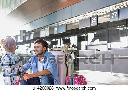 Stock Photo - Man talking to his daughter and giving her a high five in airport. Fotosearch