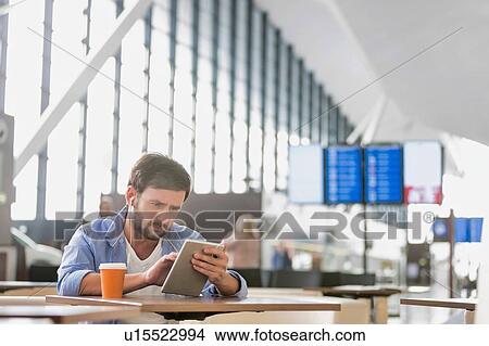 Picture - Man using digital tablet while waiting for his flight in airport. Fotosearch