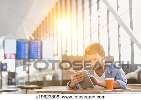 Stock Photography - Man using digital tablet while waiting for his flight in airport. Fotosearch