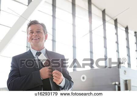 Stock Photo - Mature attractive businessman taking out his passport from his suit in airport. Fotosearch