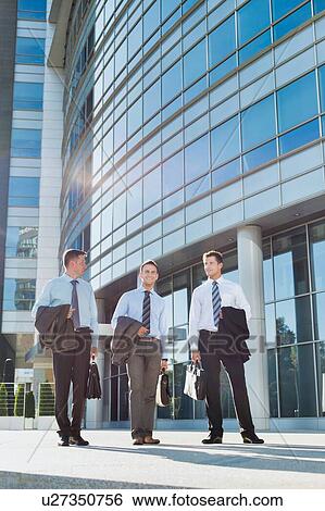Mature attractive businessmen walking while talking against office building after work View Large Photo Image Stock Photograph - Mature attractive businessmen walking while talking against office building after work. Fotosearch