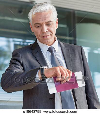 Mature businessman checking time on his watch after checked in at airport View Large Photo Image Stock Photo - Mature businessman checking time on his watch after checked in at airport. Fotosearch