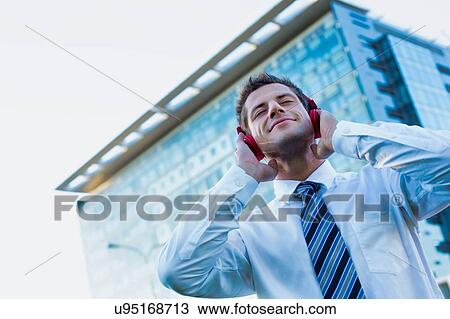 Mature businessman listening on music with headphones on View Large Photo Image Stock Image - Mature businessman listening on music with headphones on . Fotosearch