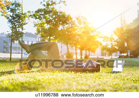 Mature businessman lying on the grass with his laptop View Large Photo Image Stock Photo - Mature businessman lying on the grass with his laptop . Fotosearch