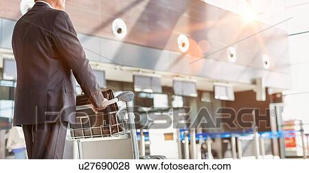 Mature businessman pushing baggage cart for check in at airport View Large Photo Image Stock Photo - Mature businessman pushing baggage cart for check in at airport. Fotosearch