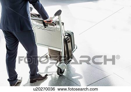 Mature businessman pushing luggage cart for check in at airport View Large Photo Image Stock Photograph - Mature businessman pushing luggage cart for check in at airport . Fotosearch