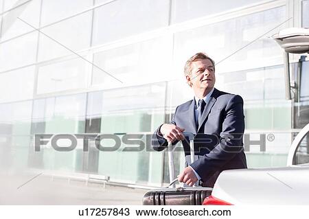 Mature businessman putting his luggage on car trunk View Large Photo Image Stock Image - Mature businessman putting his luggage on car trunk . Fotosearch