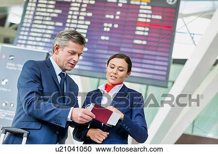 Mature businessman showing his boarding pass with the attractive airport staff View Large Photo Image Stock Image - Mature businessman showing his boarding pass with the attractive airport staff . Fotosearch