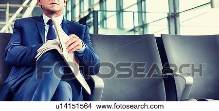 Mature businessman sitting and reading newspaper while waiting for boarding in airport View Large Photo Image Picture - Mature businessman sitting and reading newspaper while waiting for boarding in airport. Fotosearch
