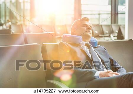 Mature businessman sitting and sleeping with his pillow while waiting for boarding in airport View Large Photo Image Stock Photo - Mature businessman sitting and sleeping with his pillow while waiting for boarding in airport. Fotosearch