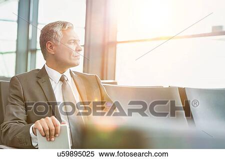 Stock Photography - Mature businessman sitting and waiting for boarding in his gate at airport. Fotosearch