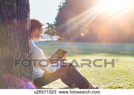 Mature businessman sitting under the tree while using digital tablet View Large Photo Image Stock Image - Mature businessman sitting under the tree while using digital tablet. Fotosearch