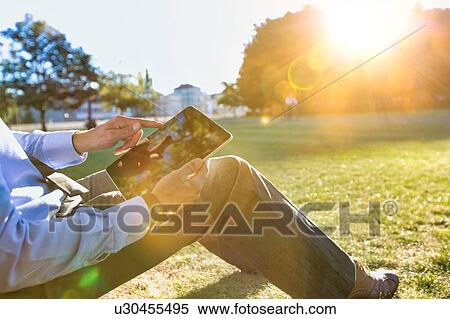 Mature businessman sitting under the tree while using digital tablet View Large Photo Image Stock Photography - Mature businessman sitting under the tree while using digital tablet. Fotosearch
