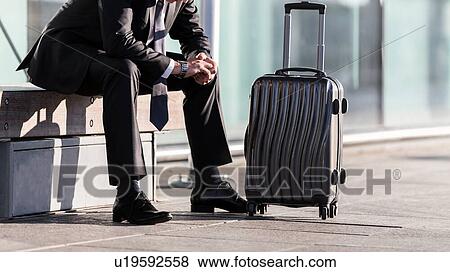Stock Photo - Mature businessman sitting while waiting in the airport. Fotosearch
