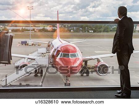 Mature businessman standing while looking on the plane in airport View Large Photo Image Stock Image - Mature businessman standing while looking on the plane in airport. Fotosearch