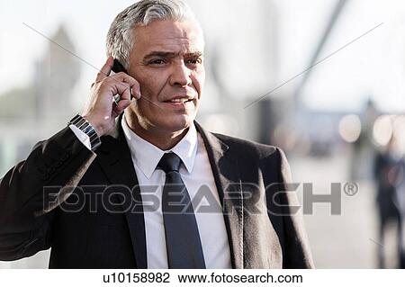Mature businessman talking on smartphone in airport View Large Photo Image Stock Image - Mature businessman talking on smartphone in airport. Fotosearch